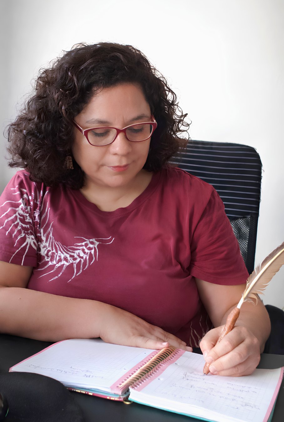 Johanna Luzmira Soto Bustos escribiendo con pluma en su cuaderno de notas de sesión.